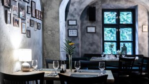 A restaurant with a rustic interior, featuring a wall adorned with framed pictures, a vase with a single flower, and a table set for dining.