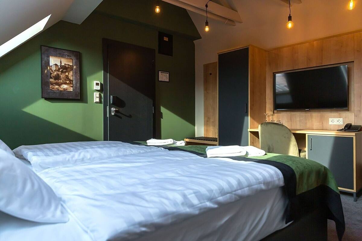 A hotel room with two beds, a desk, a TV, and a wardrobe.