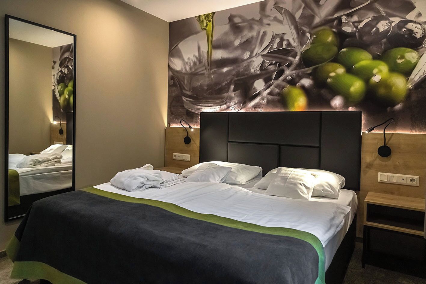 Une chambre d’hôtel avec un grand lit, un miroir et un mur orné d’un tableau.