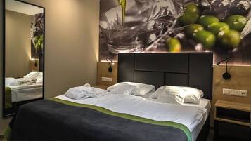 Une chambre d’hôtel avec un grand lit, un miroir et un mur orné d’un tableau.