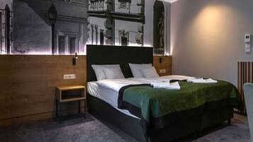 Une chambre d’hôtel moderne avec un grand lit, une petite table de chevet et une fresque murale.