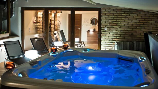 A hot tub with a blue light, a laptop, and a chair in the background.