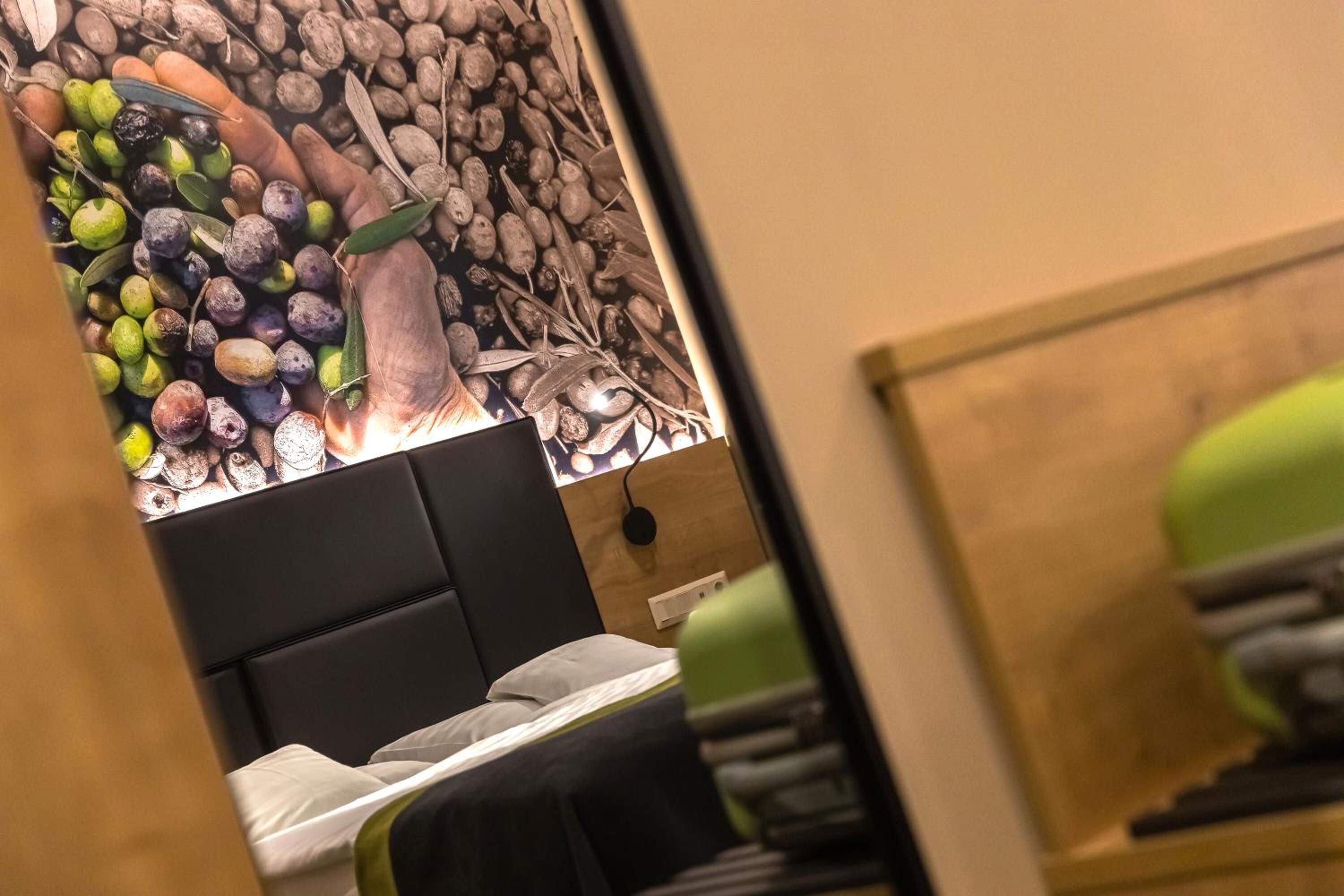 Un dormitorio con cama, cabecera y pared decorada con un motivo de frutas y frutos secos.