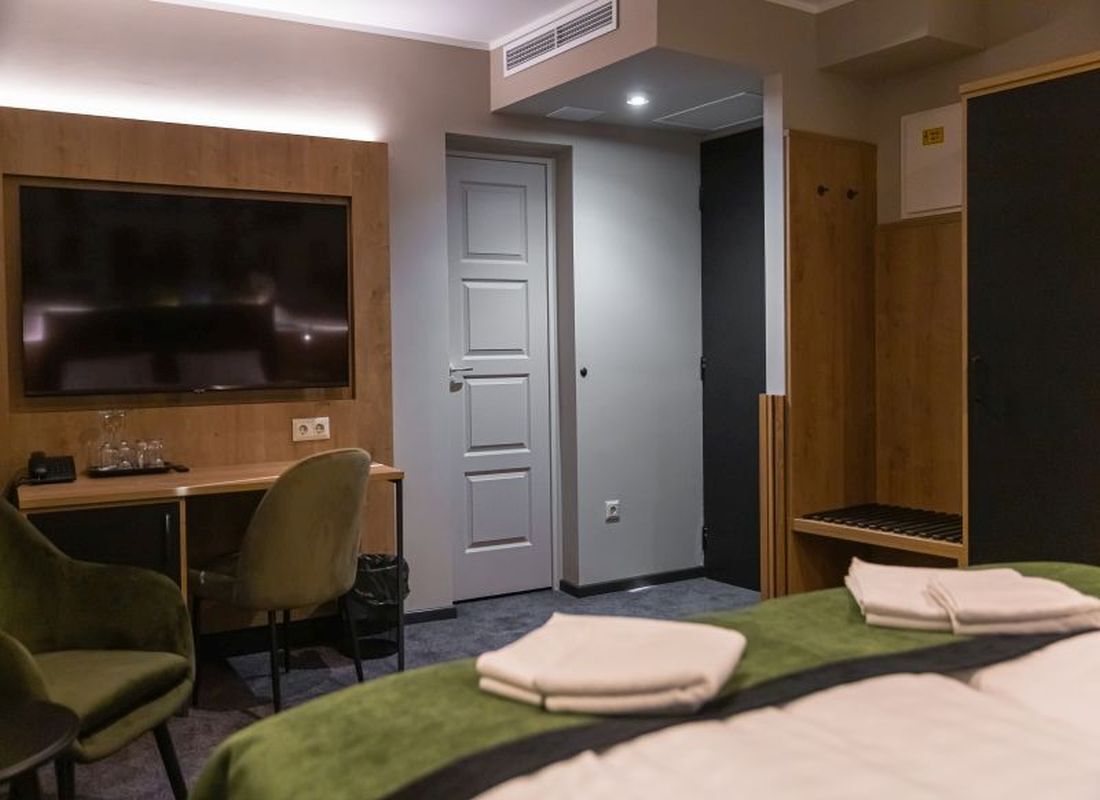 Ett hotellrum med en säng, ett skrivbord, en stol, en tv och en garderob.