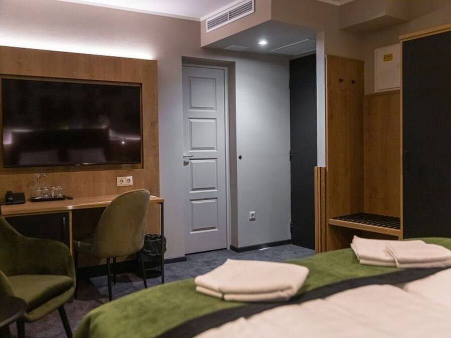 Ett hotellrum med en säng, ett skrivbord, en stol, en tv och en garderob.