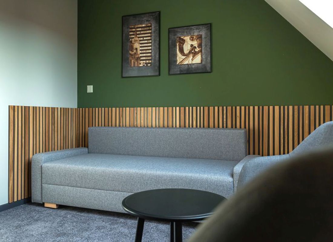 Un salon moderne avec un canapé gris, une table ronde noire et deux œuvres d’art encadrées accrochées au mur.