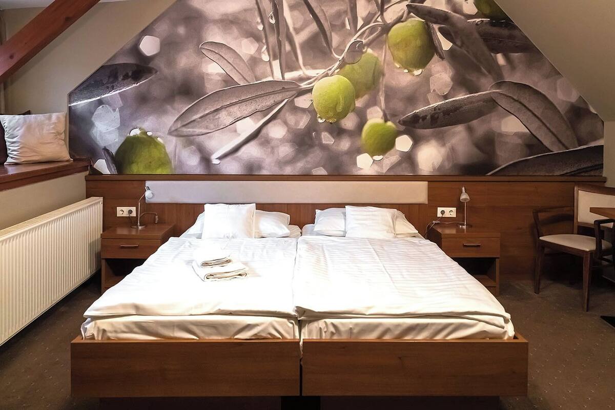 A double bed with white bedding, two bedside tables with lamps, a wooden headboard, and a large abstract wall mural.