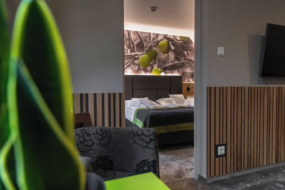 A hotel room with a bed, a chair, and a wall-mounted TV.