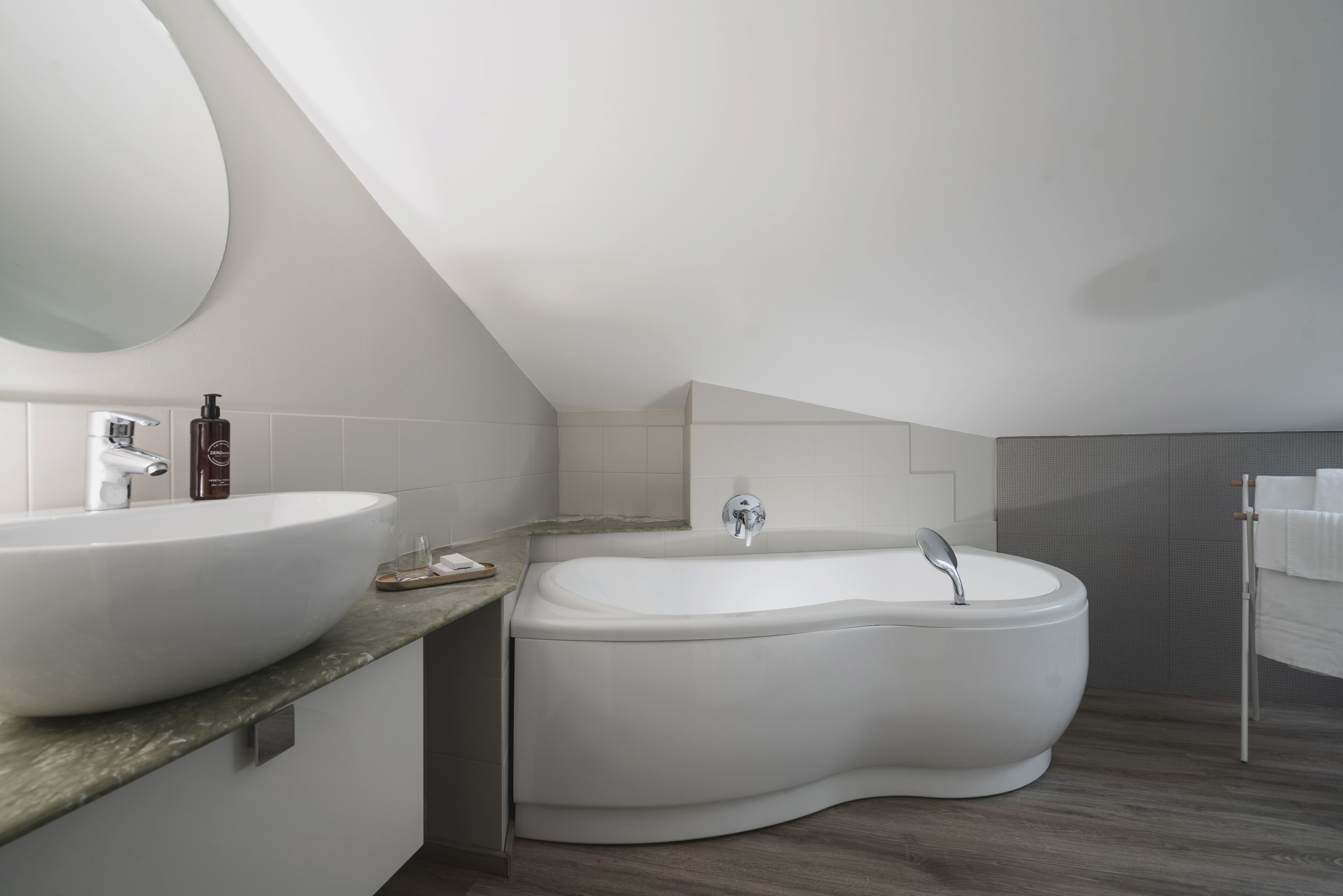 A modern bathroom with a large oval sink, a freestanding bathtub, and a large mirror.
