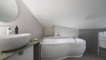 A modern bathroom with a large oval sink, a freestanding bathtub, and a large mirror.