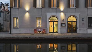 A building with a reflective pool in front, two outdoor seating areas, and a well-lit entrance. - Al Ponticello Room & Breakfast (Comacchio)