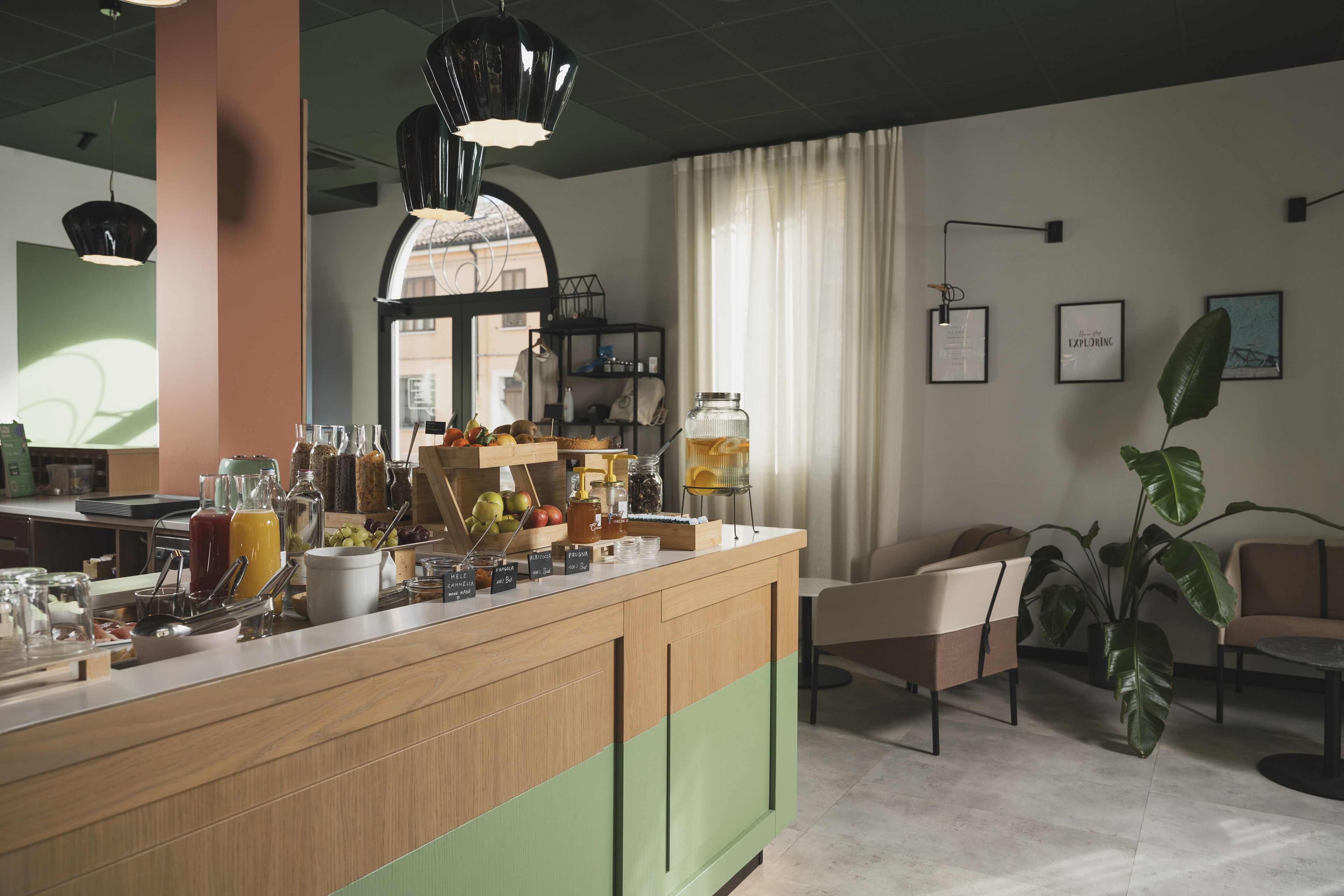 Uma área de bar moderna com balcão de madeira, diversas bebidas e um espaço com cadeiras e uma planta grande.
