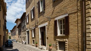 Una estrecha calle adoquinada flanqueada por edificios tradicionales de ladrillo, con pequeños balcones y ventanas con contraventanas.