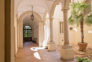 A corridor with arches, columns, and a palm tree. - Palazzo Rotati (Fano)