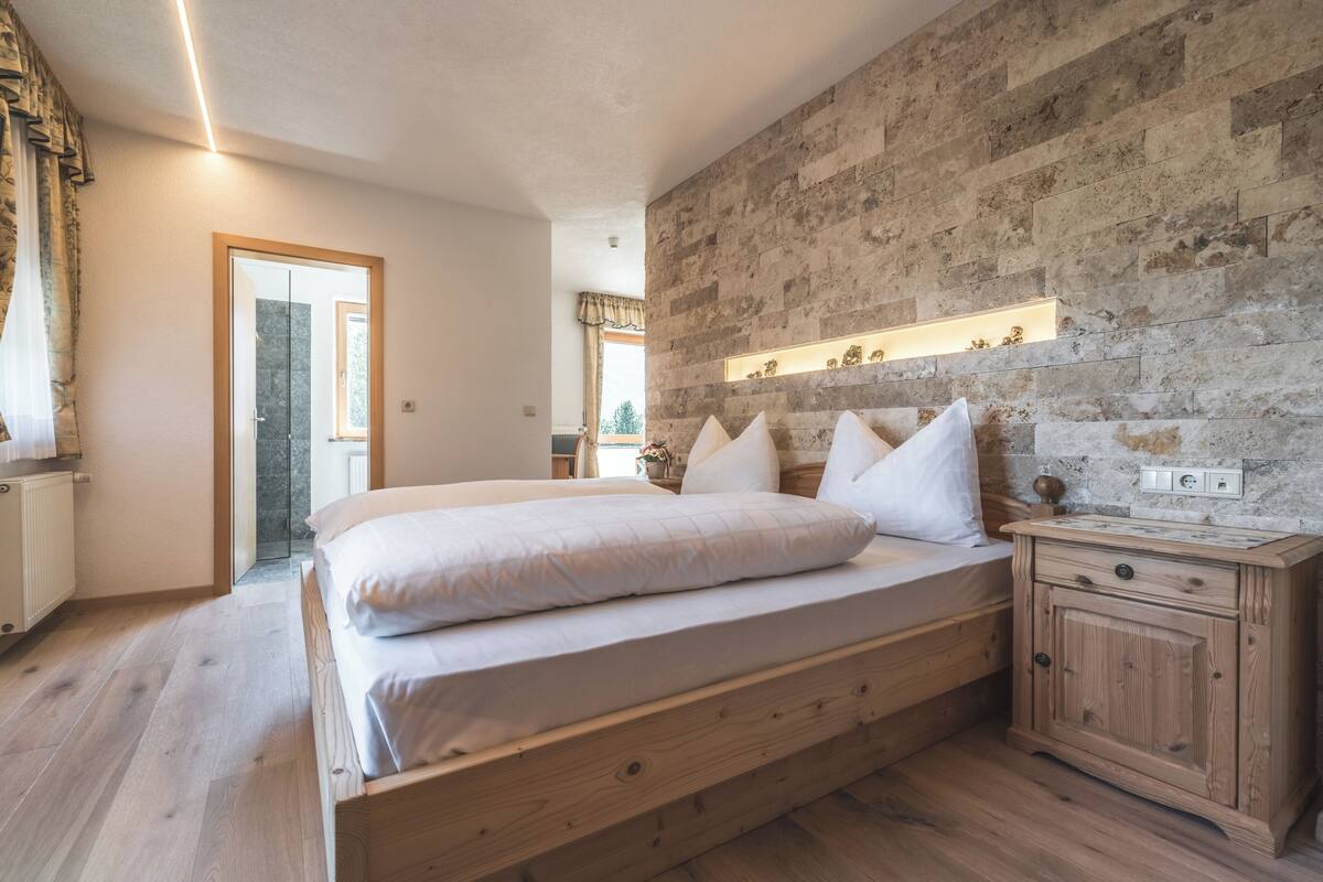 Un dormitorio con una cama de madera, una mesita de noche y una pared de piedra.