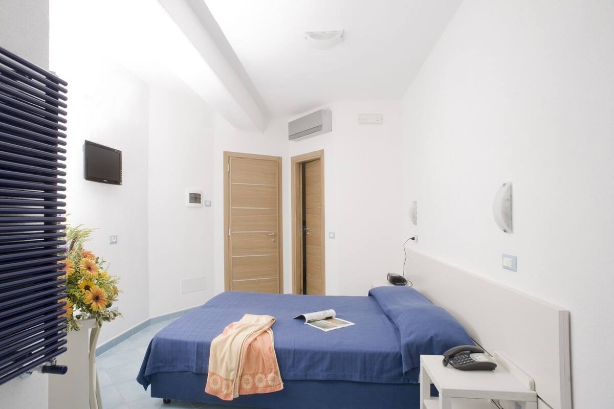 A bedroom with a bed, bedside table, and a wall-mounted TV.