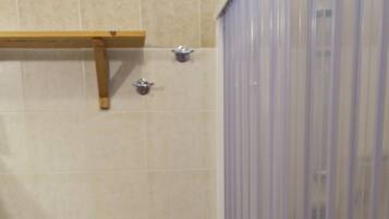 Un baño con inodoro, lavamanos, cortina de ducha y cubo de basura.