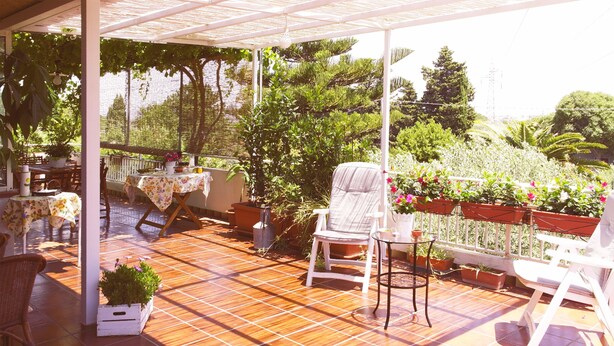 A covered patio with a tiled floor, outdoor furniture, and potted plants. - Giogaia Bed & Breakfast (Modica)