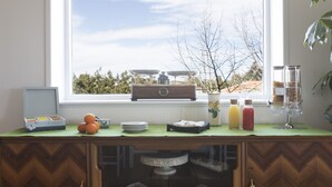 A kitchen counter with a window view, a fruit bowl, plates, a coffee maker, and a tea kettle. - Giogaia Bed & Breakfast (Modica)