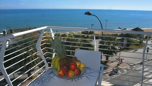 Un balcon avec un panier de fruits et une vue sur l’océan.