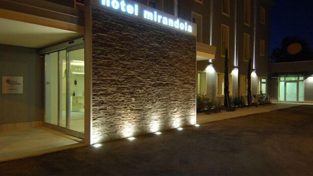 A hotel named 'Mirandola' with a stone facade, entrance doors, and a well-lit exterior. - Hotel Mirandola (Mirandola)