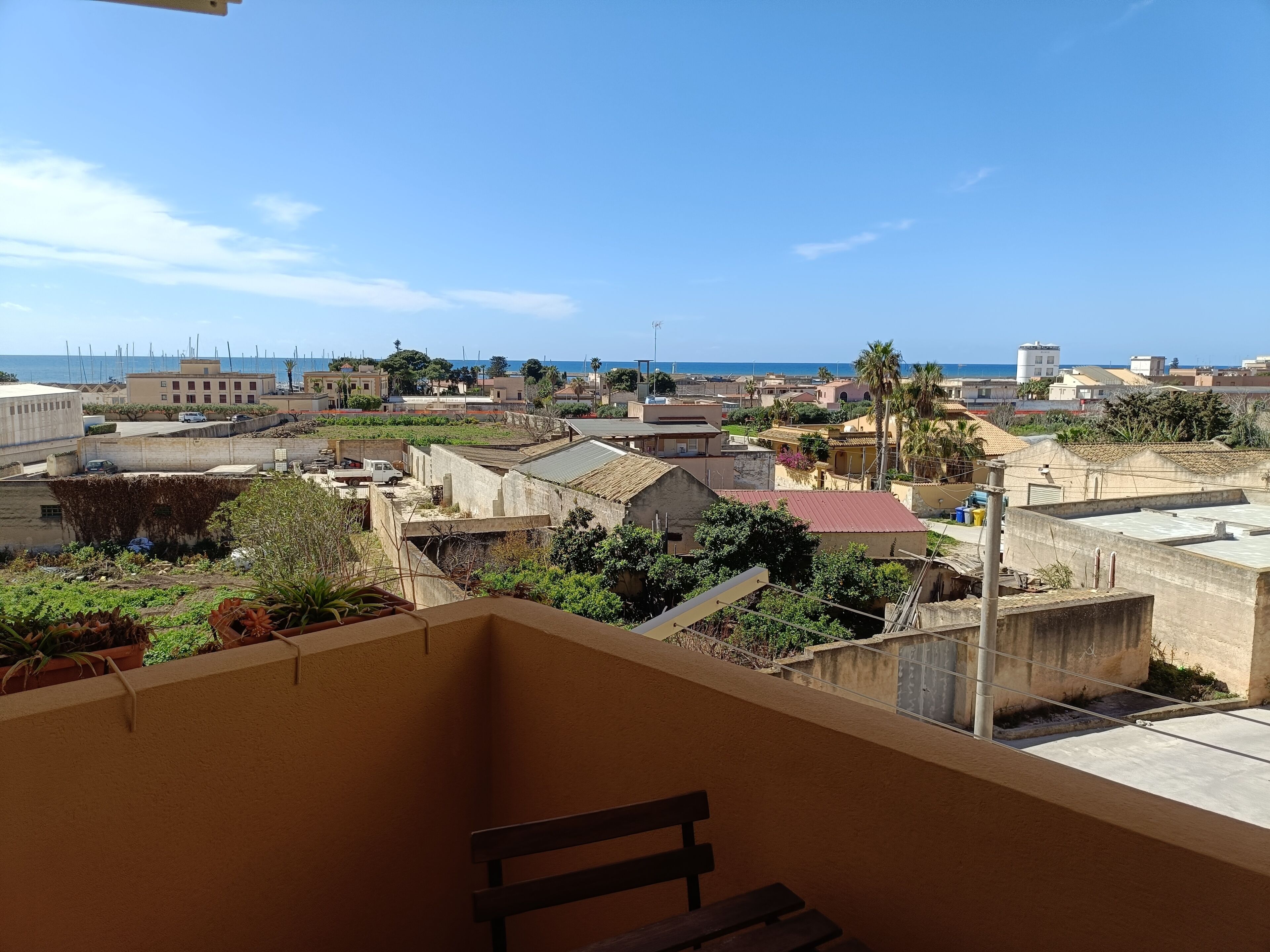 Un balcón con vistas a un pueblo costero, edificios y cielo despejado.