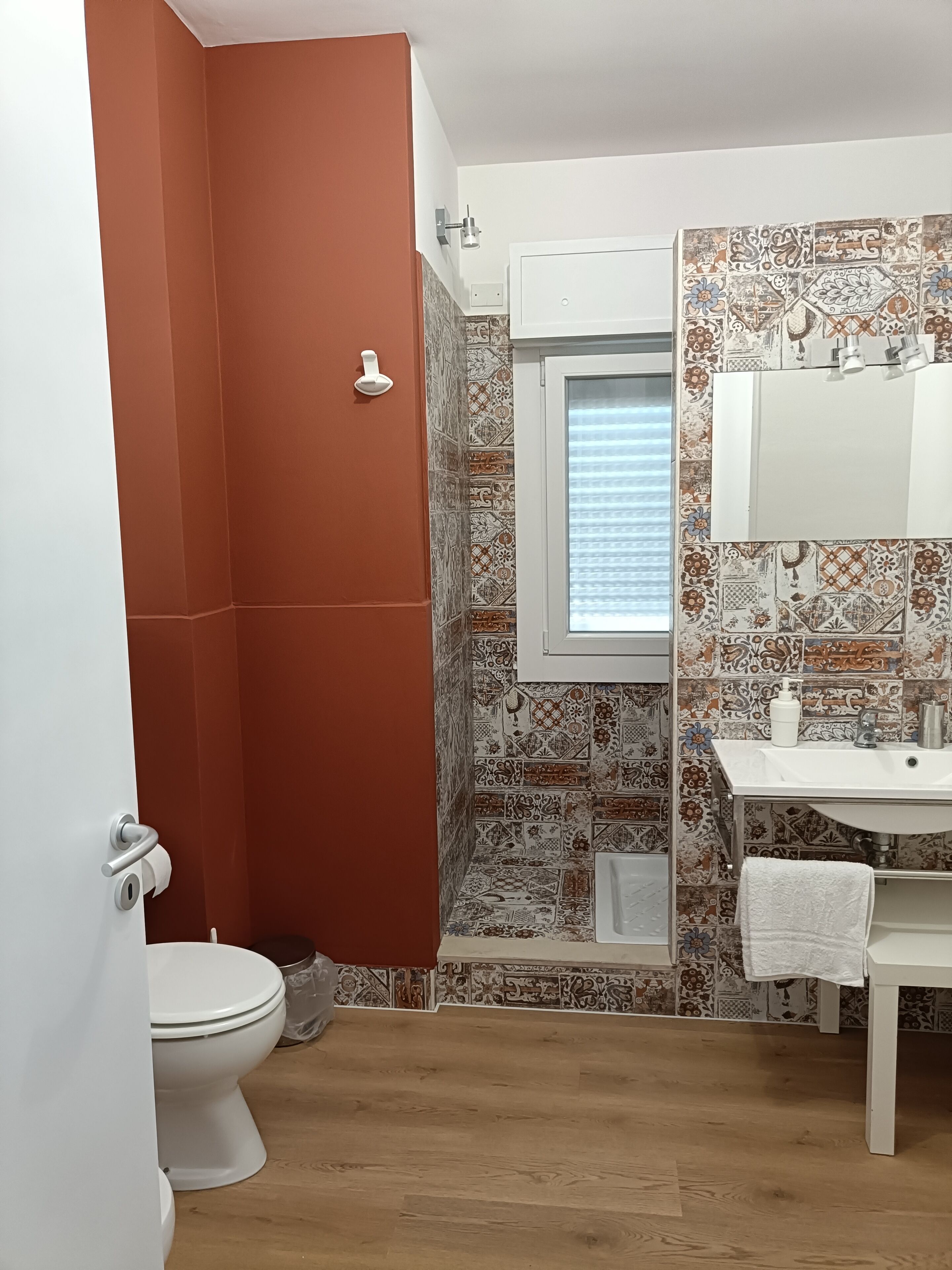 Baño con inodoro, ducha, lavamanos y ventana.
