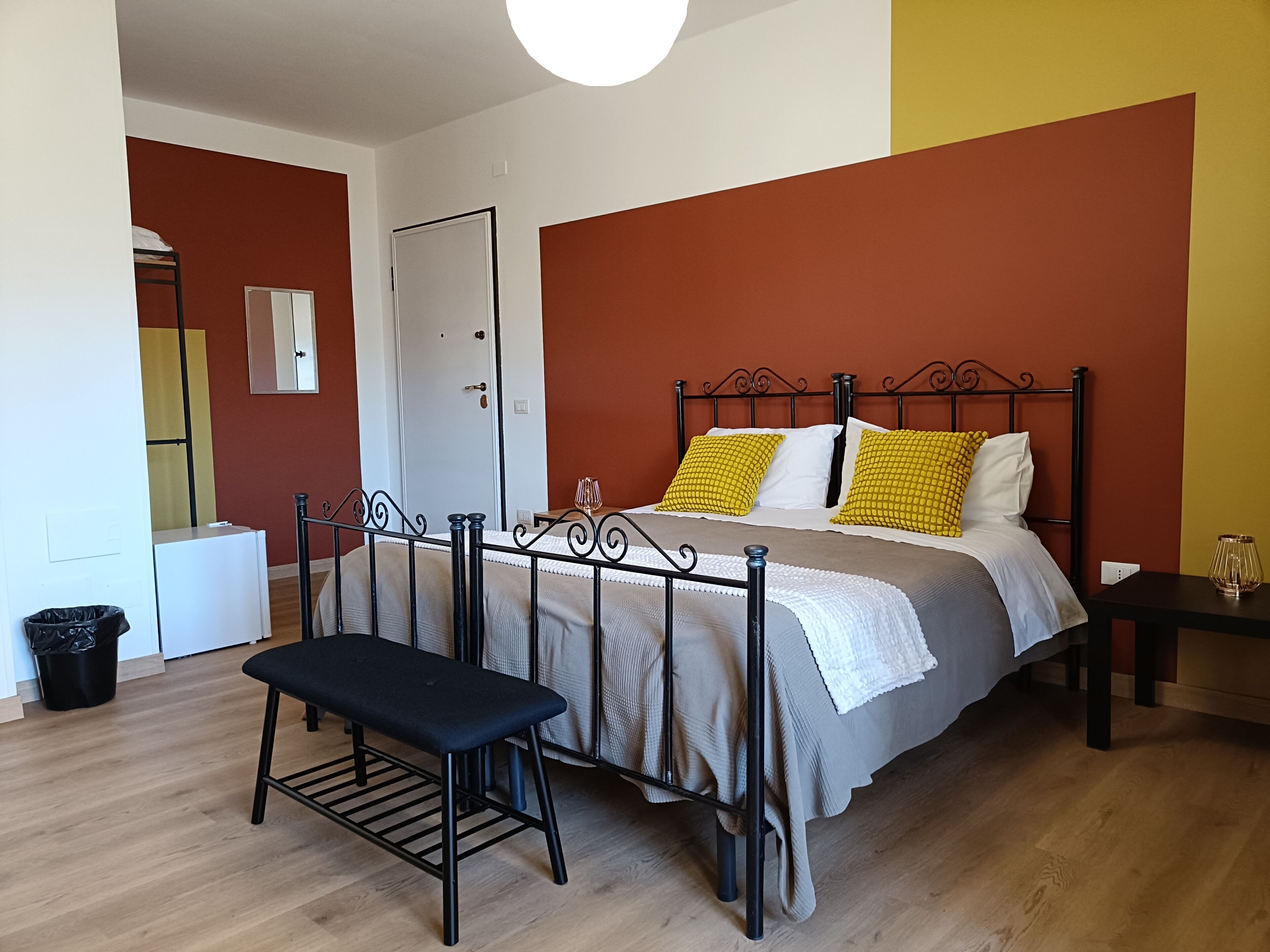 Una camera da letto con un letto, una panca, un comodino e una porta.
