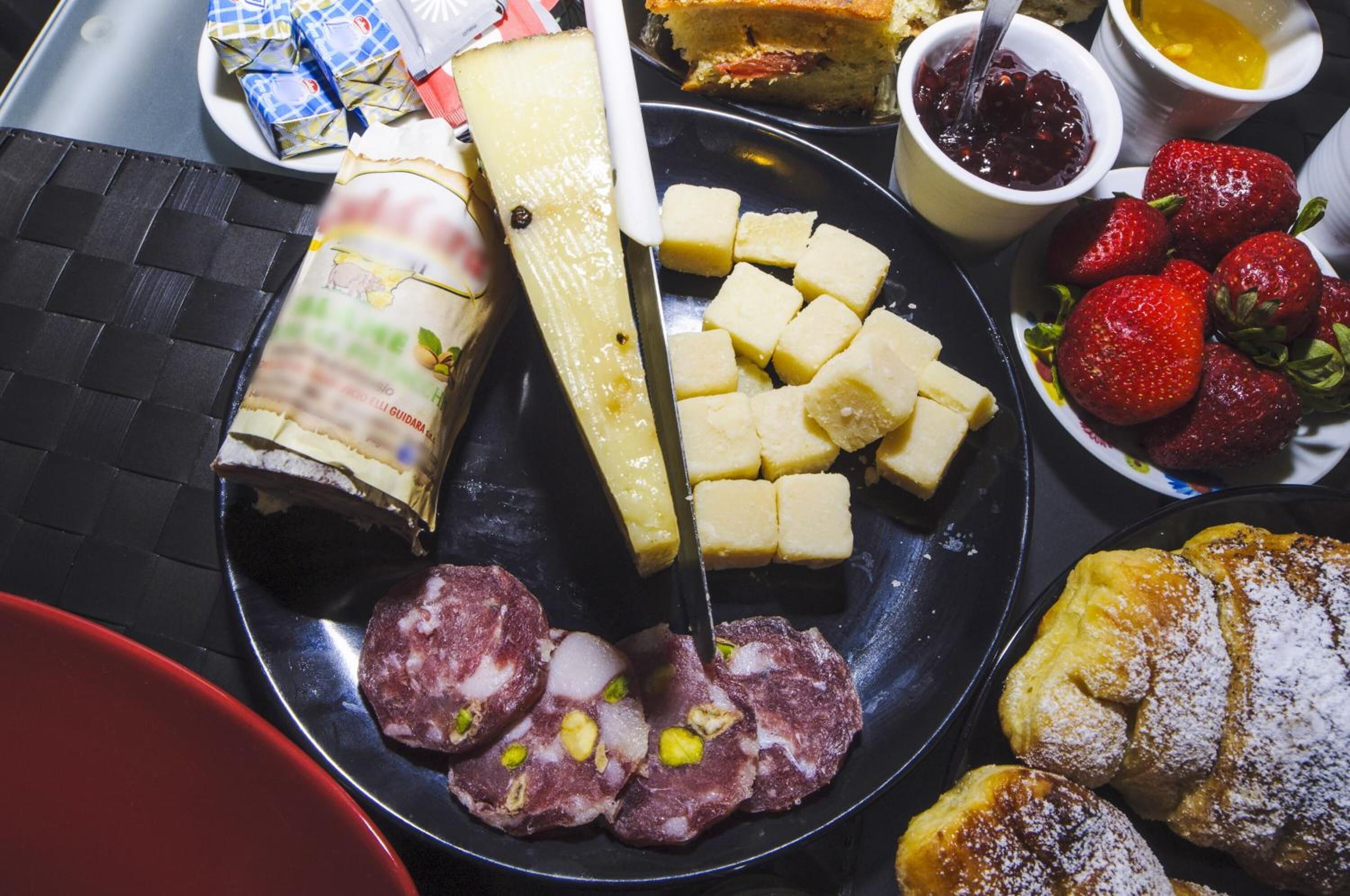 A variety of food items including cheese, strawberries, and pastries on a plate.