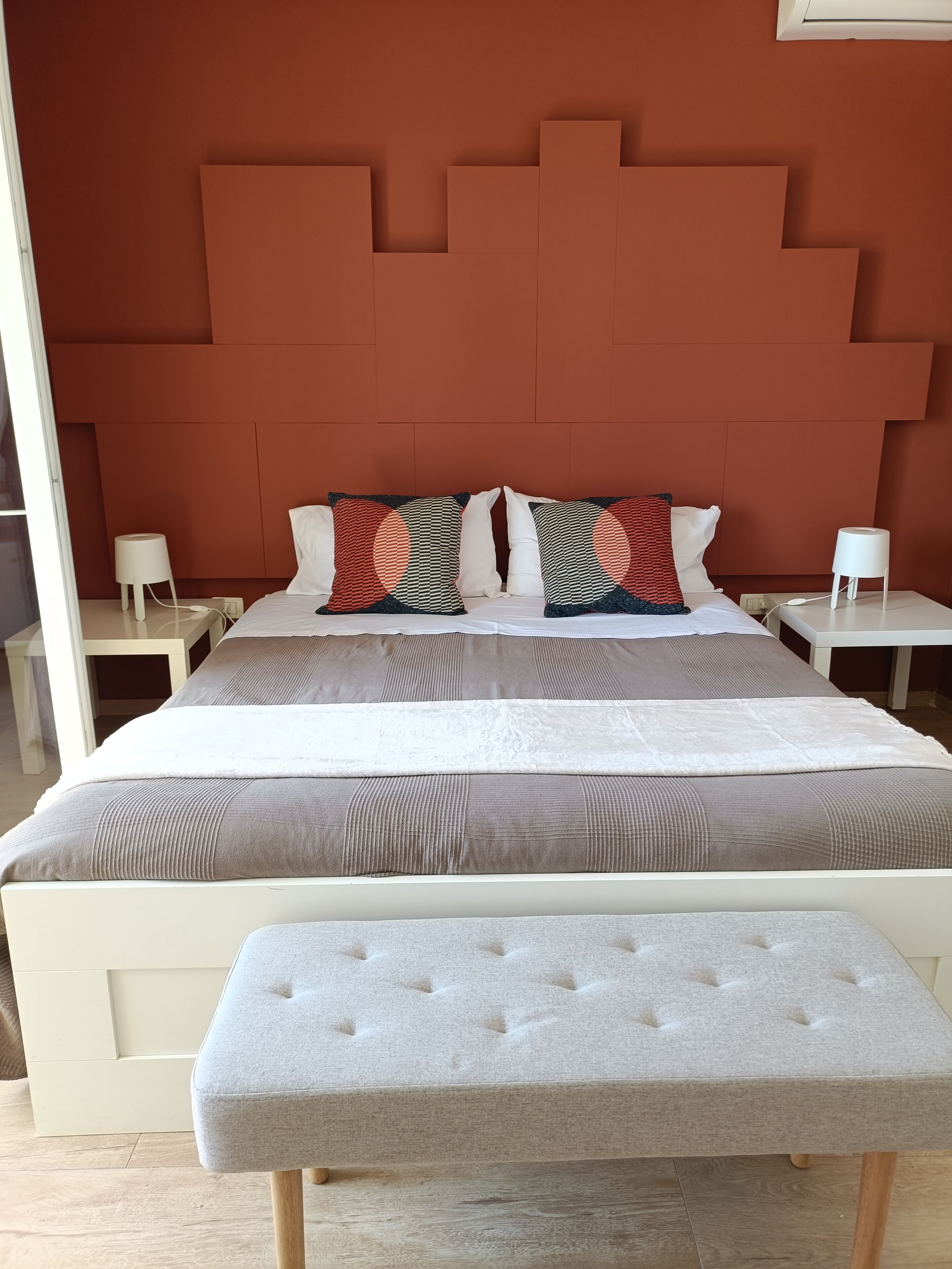 A bed with a headboard, two bedside tables, and a bench.