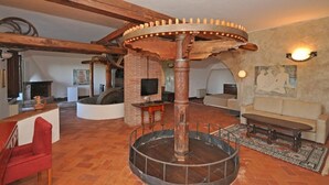A rustic interior with exposed wooden beams, a central wooden column, a fireplace, a sofa, and a television. - Villa Camaiore (Camaiore)