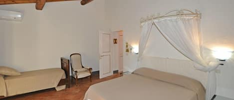 Un dormitorio con dos camas, una silla, una puerta y una cama con dosel e iluminación.