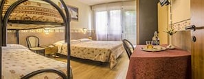 A hotel room with two beds, a dining table with a red tablecloth, and a window with curtains. - Piccolo Hotel Tanamalia (Lizzano in Belvedere)