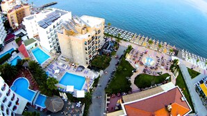 A resort with multiple swimming pools, a beach area with sun loungers, and a view of the sea. - Yunus Beach Hotel (Marmaris)