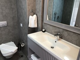 A bathroom with a white sink, a mirror, a towel rack, and a toilet.