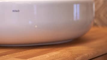 A white Kolo bowl on a wooden countertop.