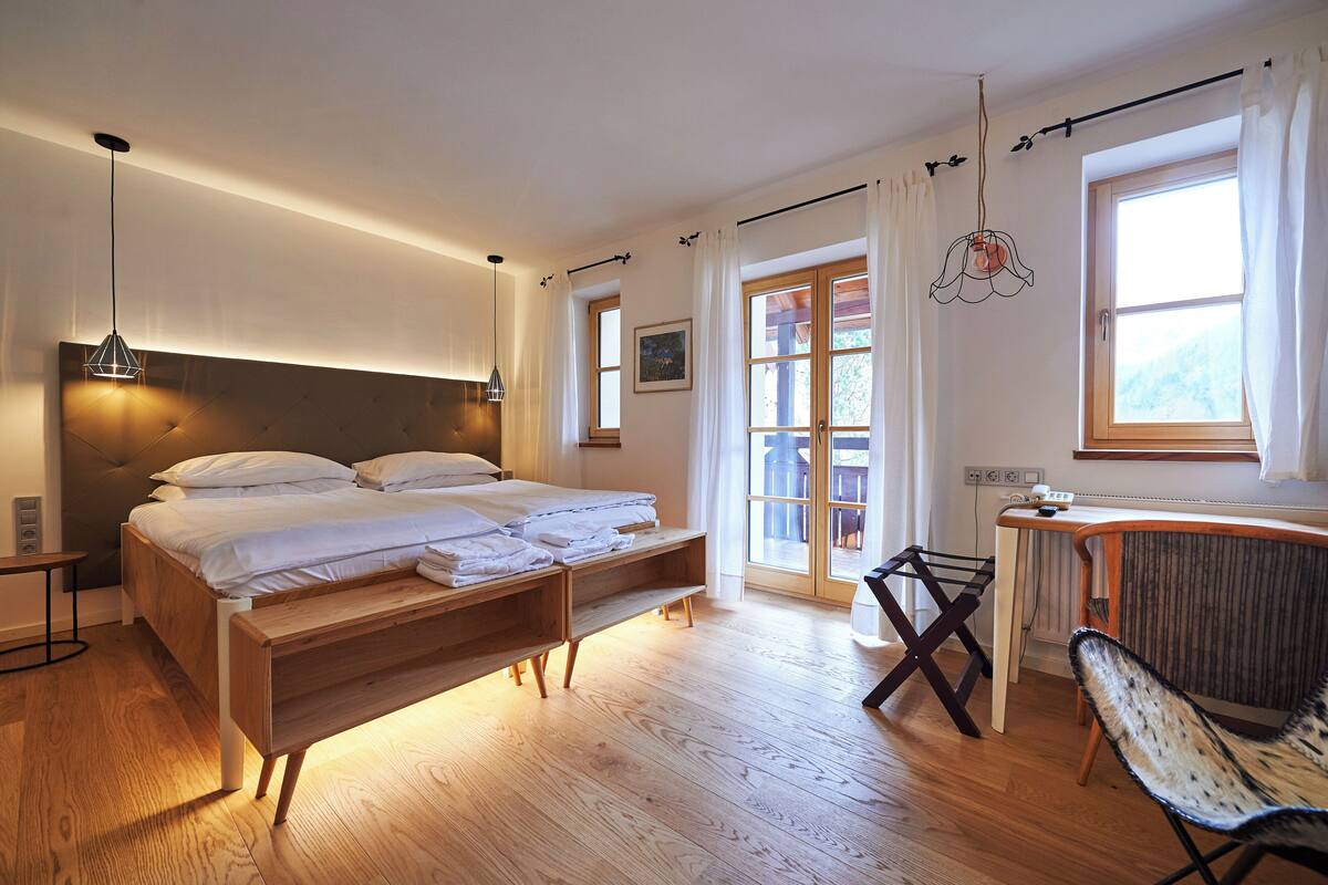 A bedroom with a bed, bedside tables, a desk, and a chair.
