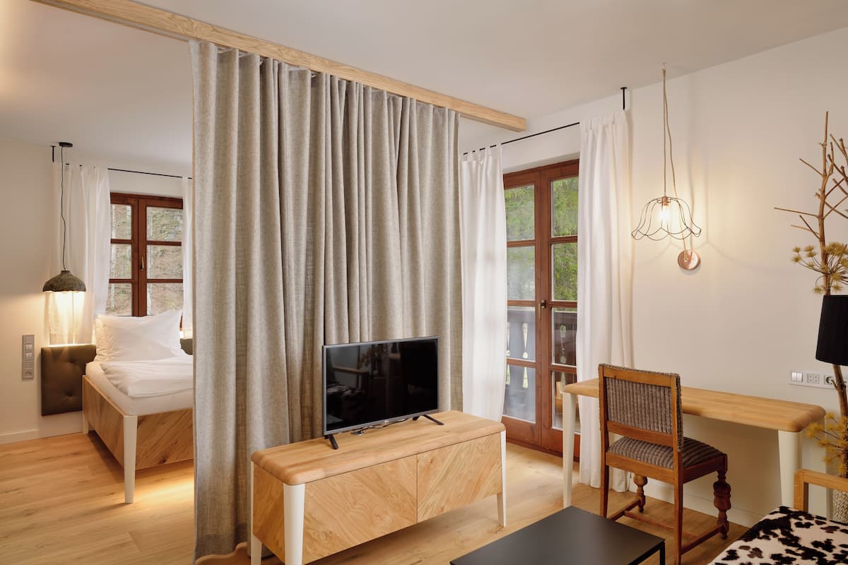 A modern bedroom with a bed, TV, wooden desk, and chair.