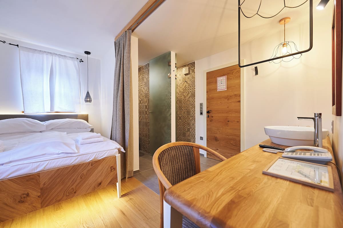 A hotel room with a wooden bed, a desk with a sink, a chair, and a map on the desk.