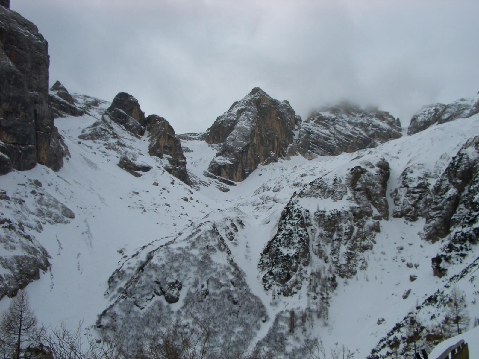 Paisagem montanhosa com picos cobertos de neve e terreno rochoso.