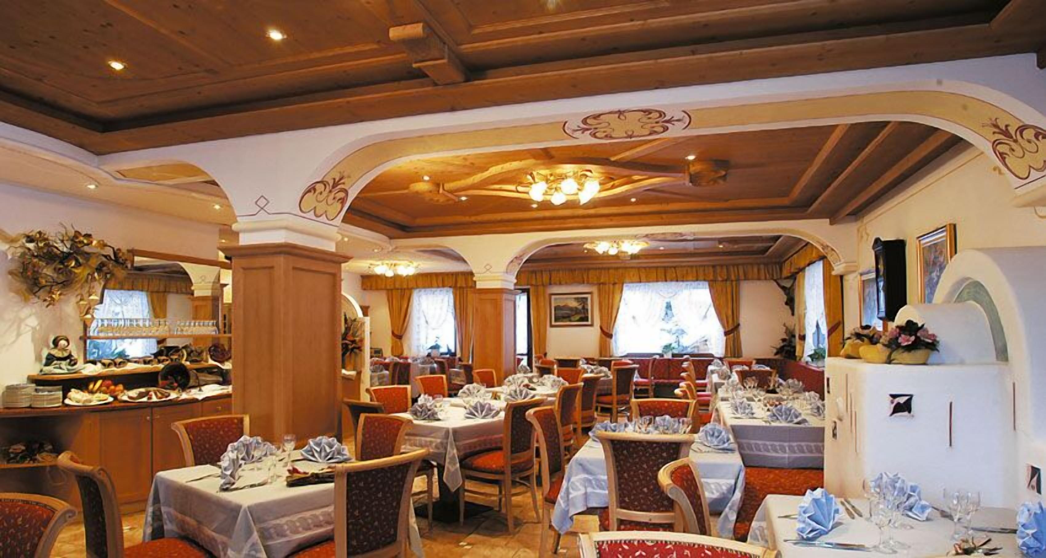A restaurant with wooden beams, chandeliers, and tables set for dining.