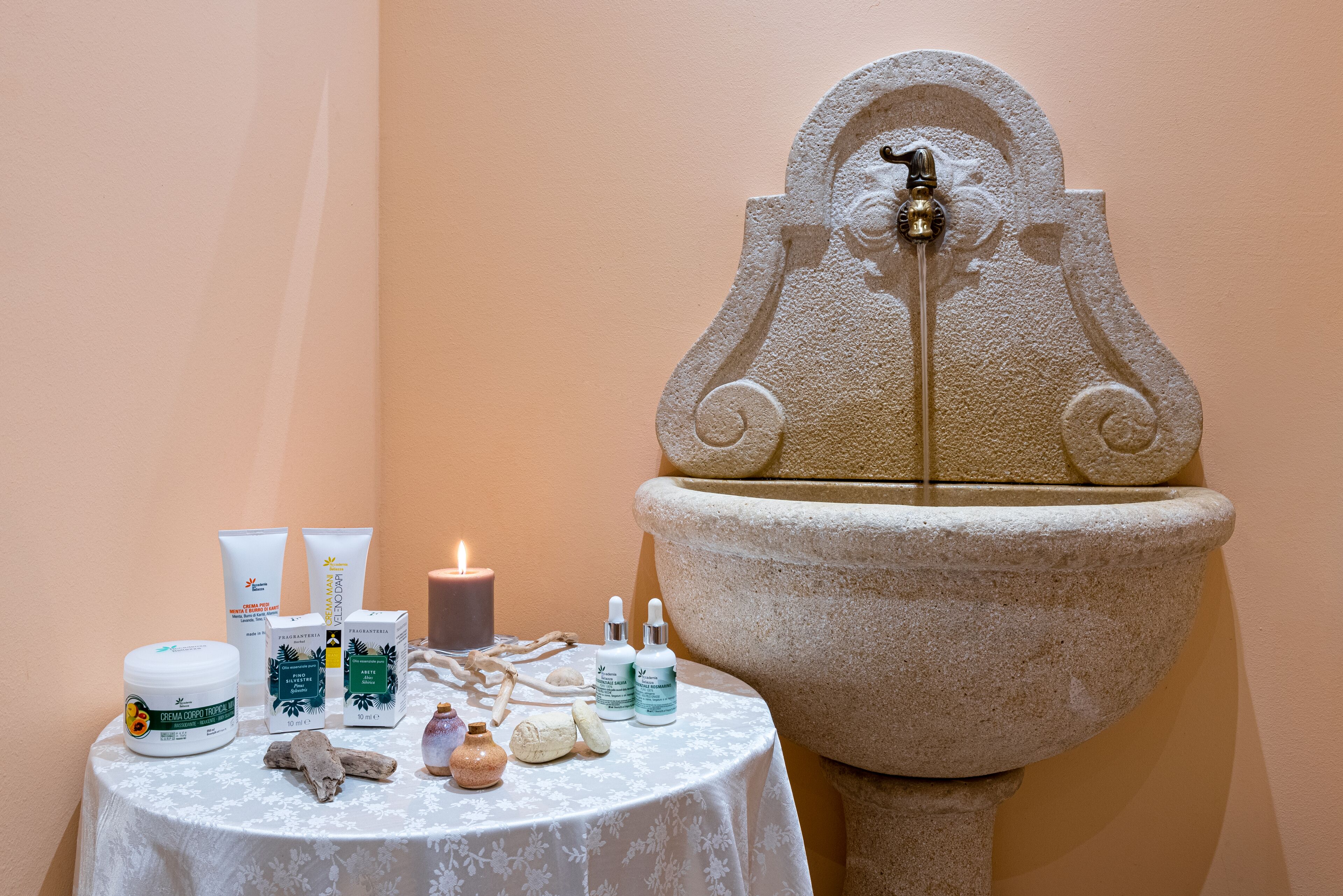 A stone fountain with a candle and spa products on a table.