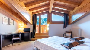 A bedroom with a bed, desk, chair, and a view of a balcony. - Hotel La Perla (Ravascletto)