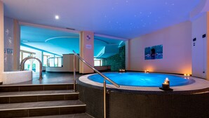 A spa area with a hot tub, steps leading to it, and a wall with a picture. - Hotel La Perla (Ravascletto)
