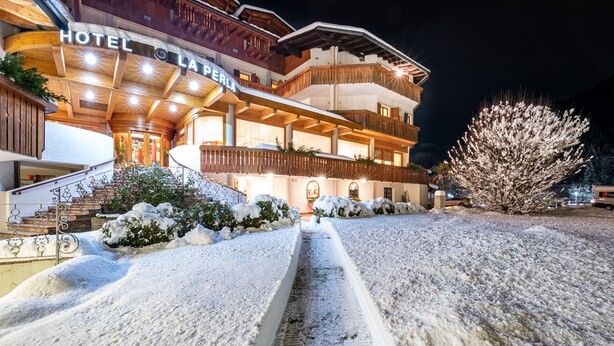 A multi-story hotel with a wooden facade and a sign reading "HOTEL LA PERLA". - Hotel La Perla (Ravascletto)