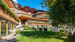 A hotel with multiple balconies, outdoor seating, and a well-maintained lawn. - Hotel La Perla (Ravascletto)
