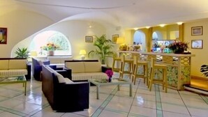 A hotel lobby with a high ceiling, a reception desk, seating area with sofas and chairs, and a tiled floor. - Central Park Hotel Terme (Ischia)