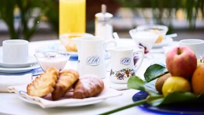A breakfast table with croissants, a pitcher, cups, and fruits. - Central Park Hotel Terme (Ischia)