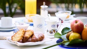 A breakfast table with croissants, a pitcher, cups, and fruits. - Central Park Hotel Terme (Ischia)