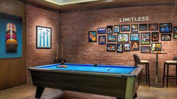Enjoy a game of pool in a lively room with a pool table, framed sports memorabilia, and bar stools.